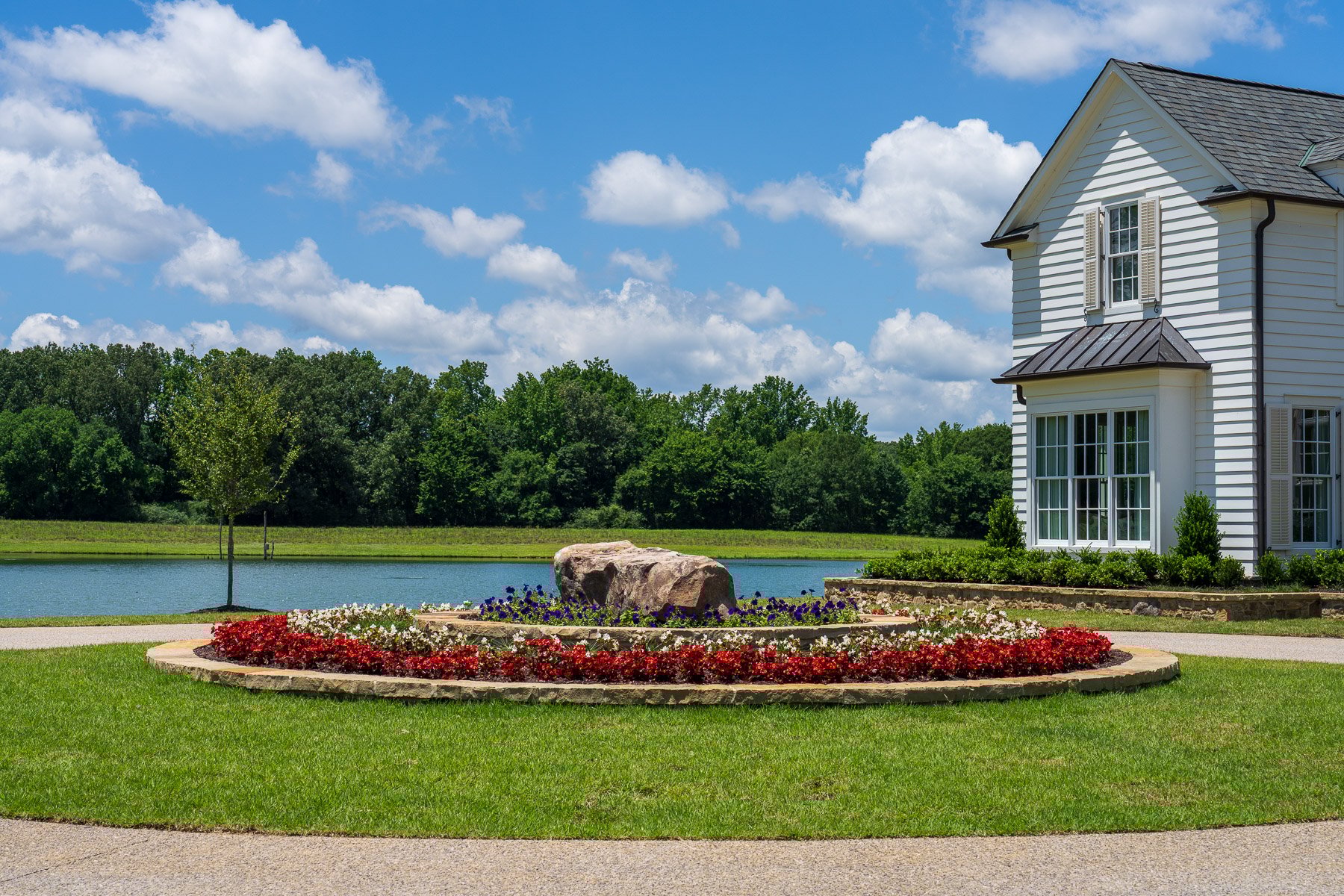 nice flower bed planting bed landscape home driveway stone shrubs trees water